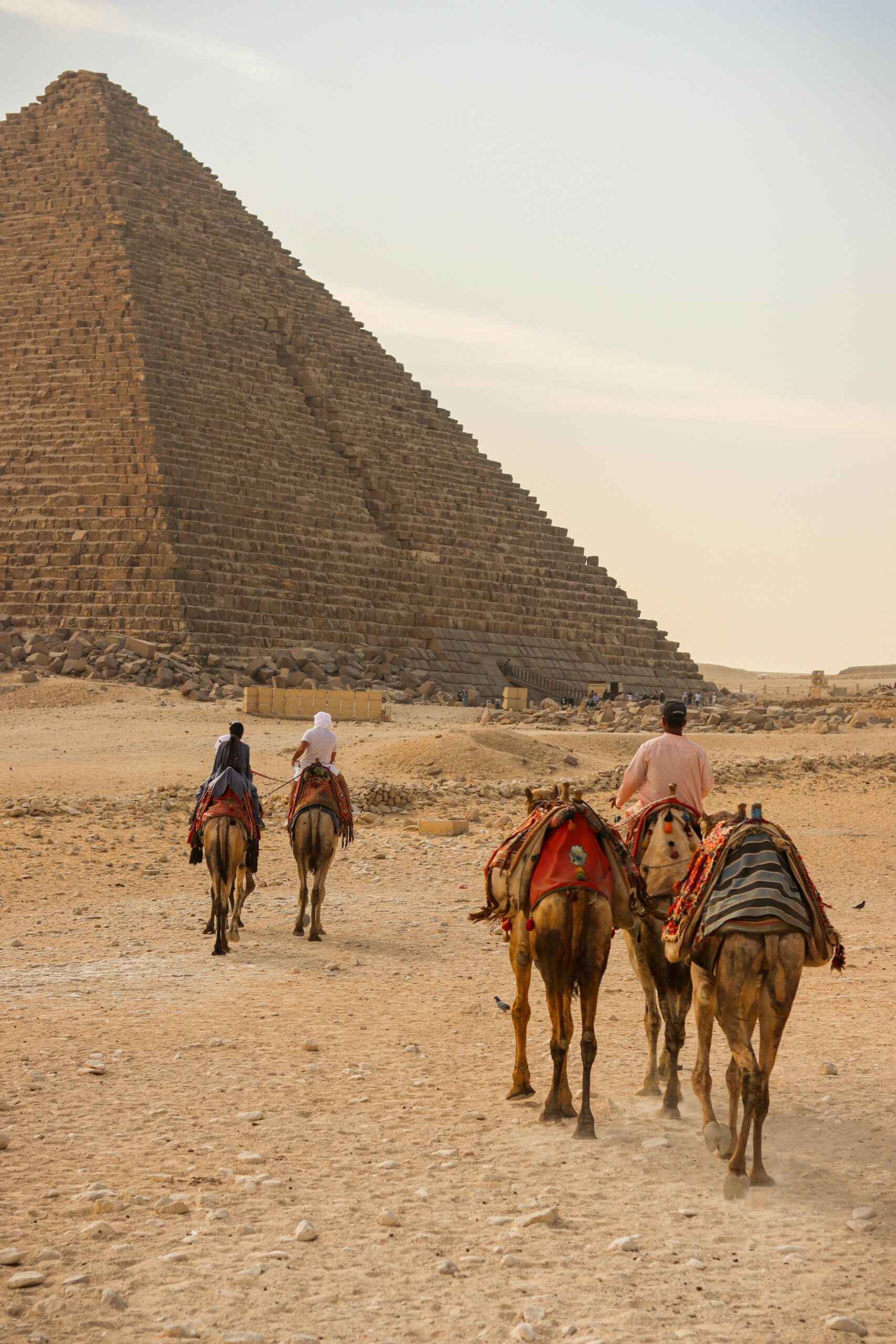 A group rides camels near an ancient pyramid in Egypt's Sahara Desert.